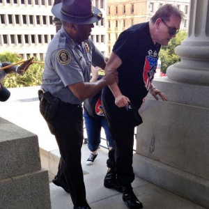 FILE - In this July 18, 2015 photo provided by Rob Godfrey, police officer Leroy Smith, left, helps a man wearing National Socialist Movement attire up the stairs during a rally in Columbia, S.C. Smith, the director of South Carolinas public safety agency, said Monday, July 20, 2015, he hopes the photo that shows him helping the white man wearing a racist T-shirt will be a catalyst for people to work toward overcoming hate and violence. (Rob Godfrey via AP, file)